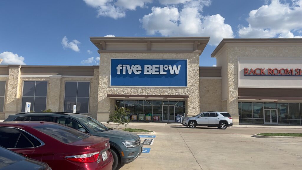 Fachada de una tienda Five Below con el rótulo azul y blanco visible sobre la entrada.