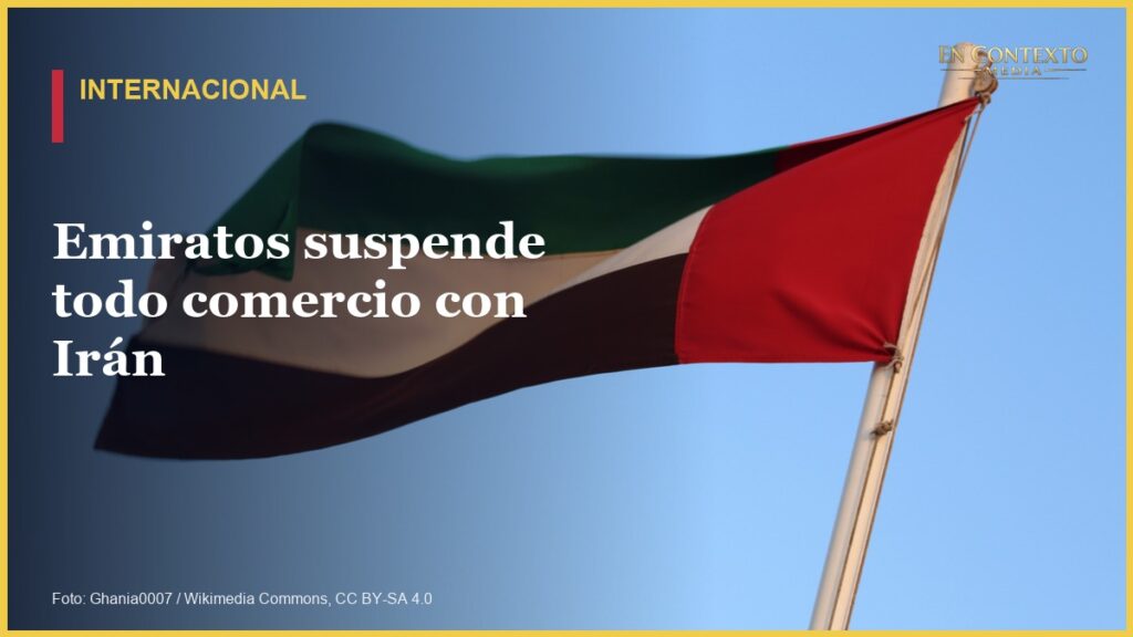 Bandera de Emiratos Árabes Unidos ondeando frente a un cielo azul.